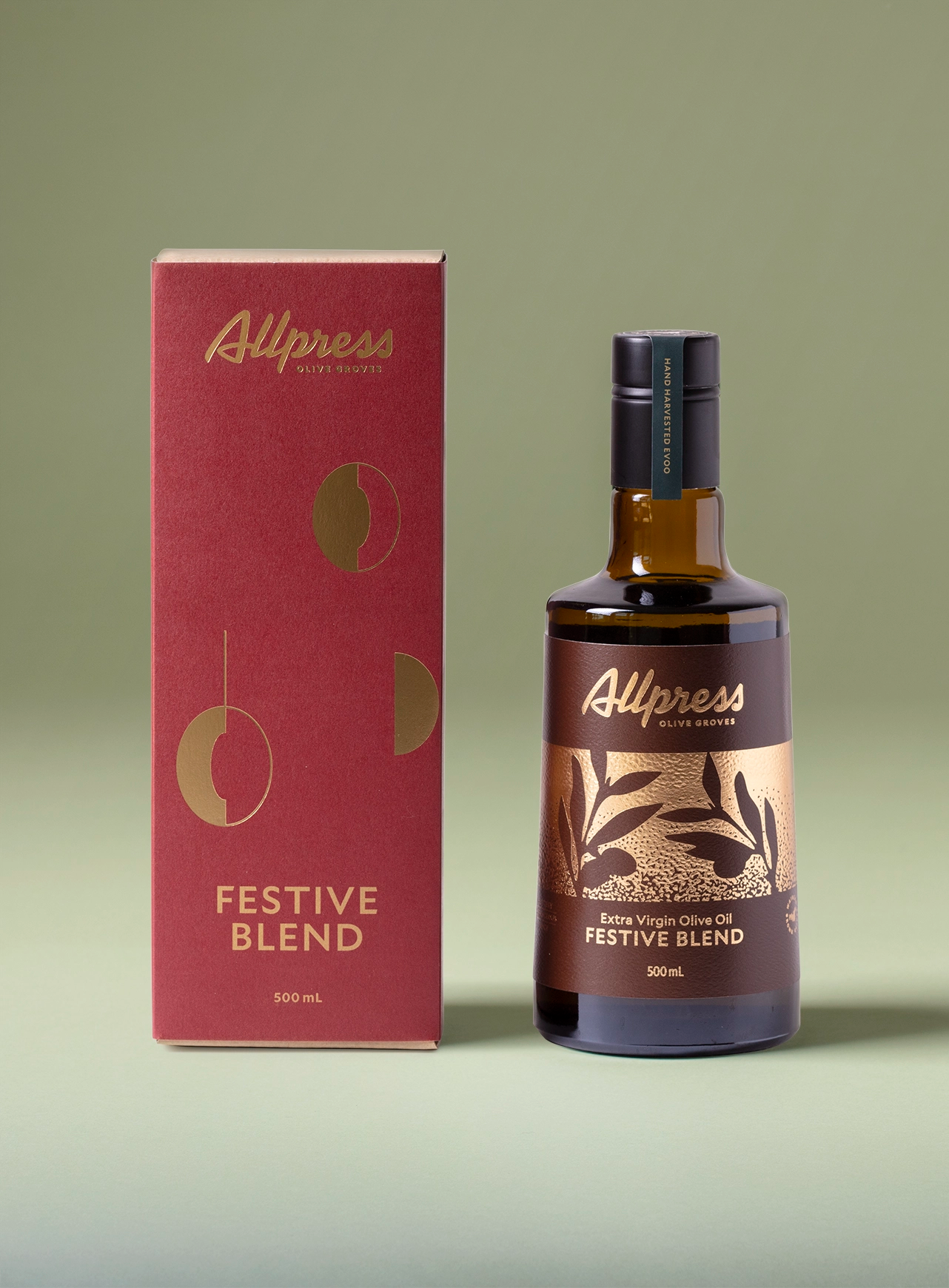A bottle of Allpress Olive Groves Festive Blend Extra Virgin Olive Oil 500ml, next to its red and gold gift box packaging.