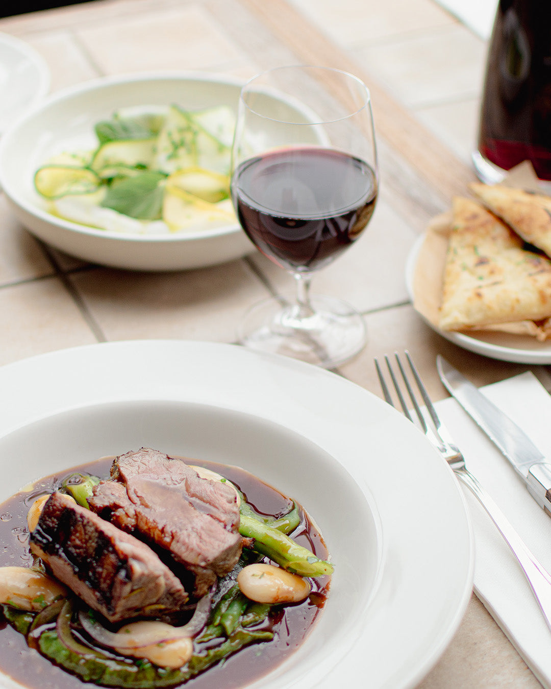 A dish with meat from Bistro Allpress with a glass of red wine