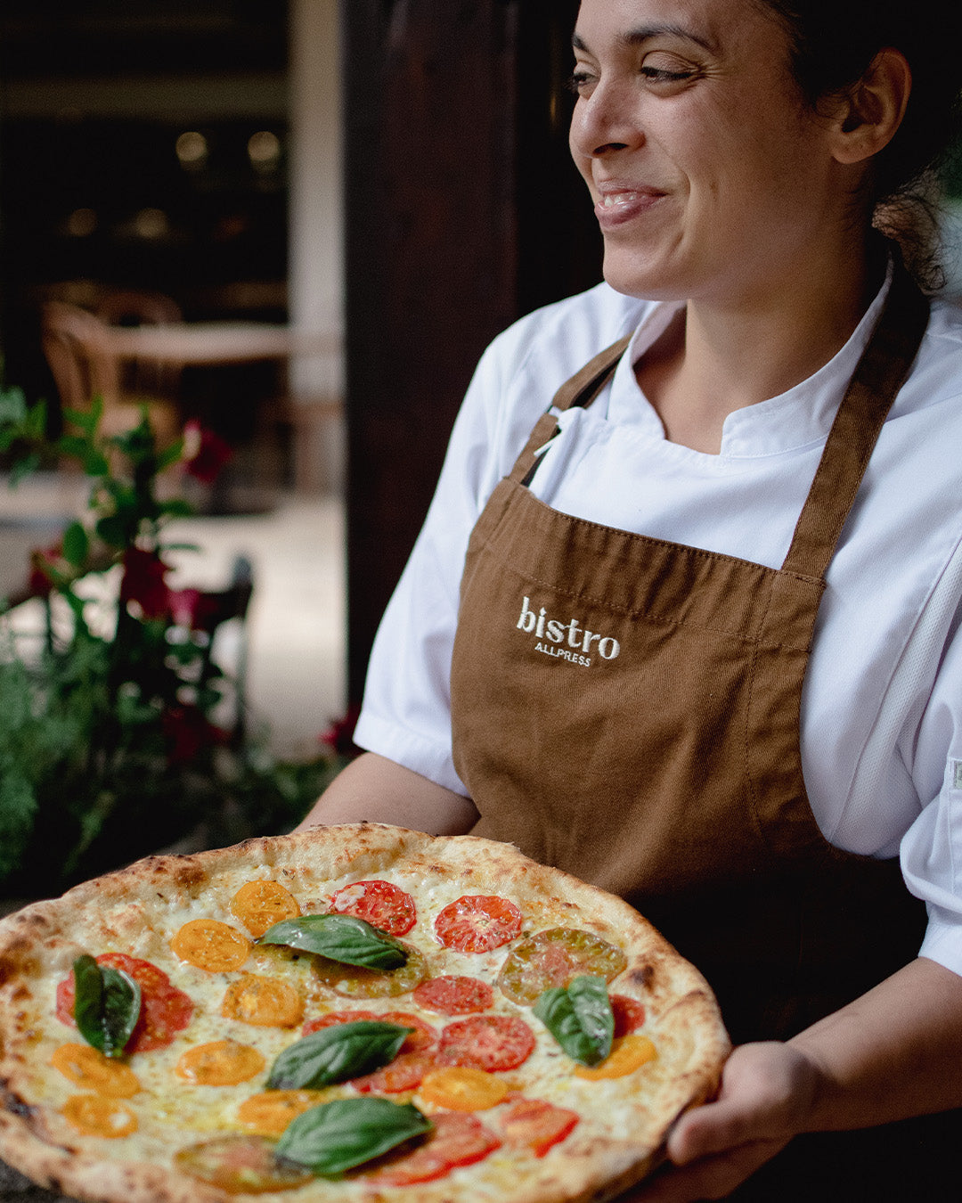Bistro Allpress Valentina holding a Heirloom Tomato Pizza