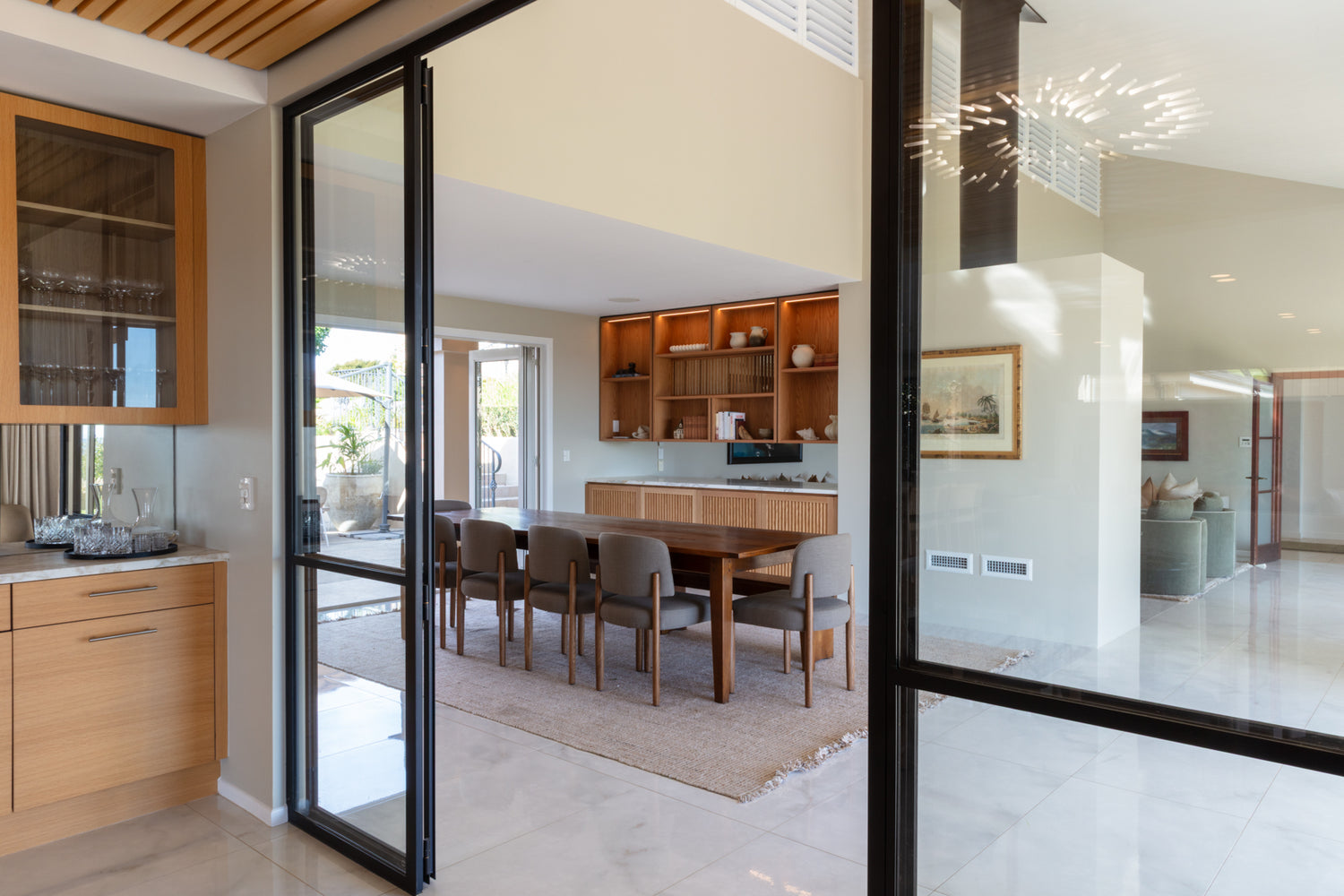 Modern kitchen and dining area with wooden cabinetry and glass doors opening to Hauraki Gulf views