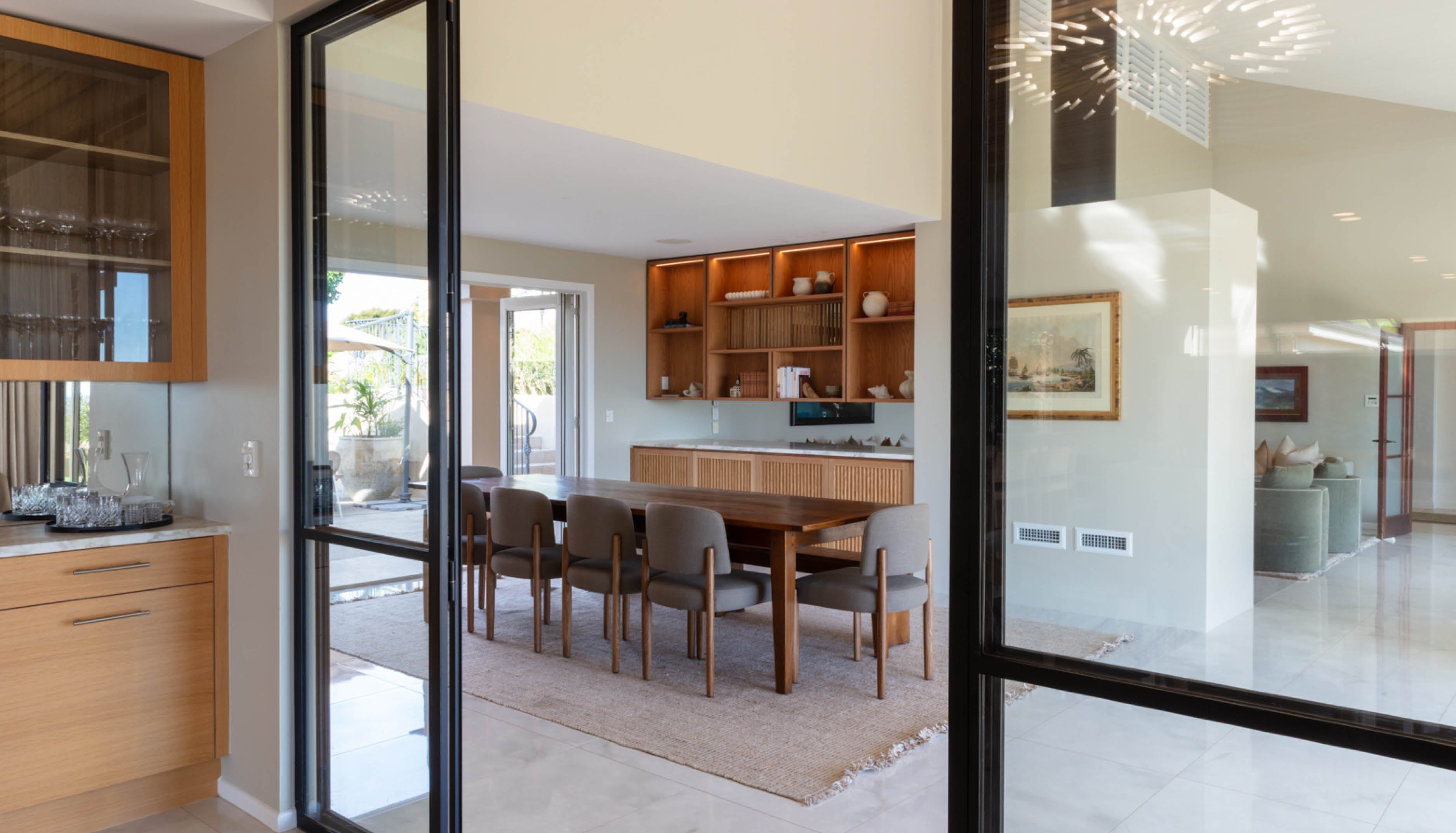 Modern kitchen and dining area with wooden cabinetry and glass doors opening to Hauraki Gulf views