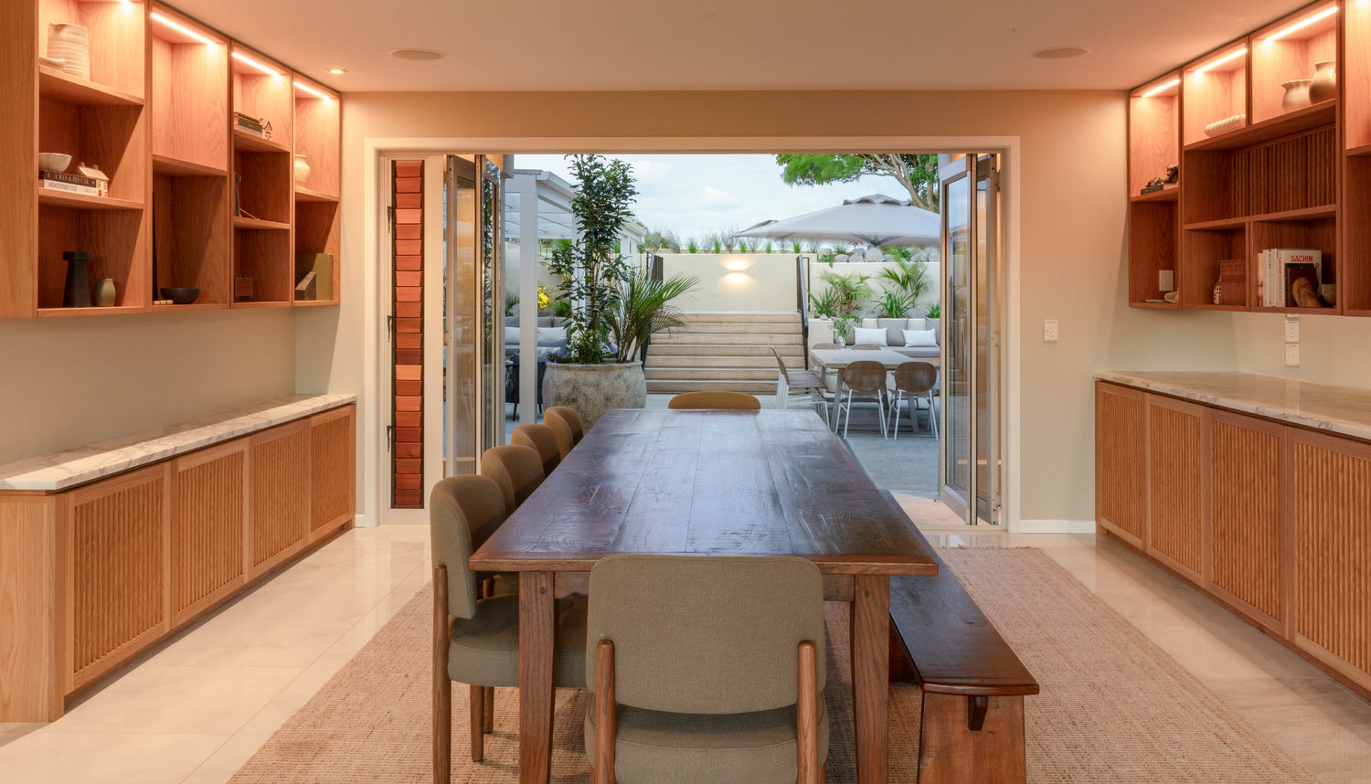 Modern dining area with large table and floor-to-ceiling windows overlooking the outdoor patio