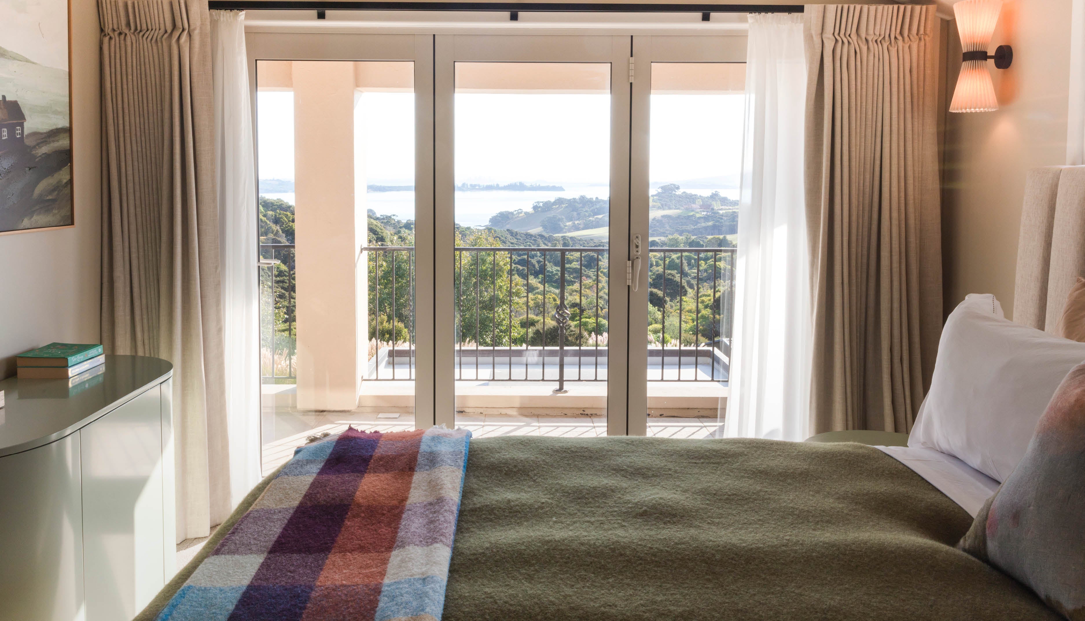 Bedroom with a large window offering a scenic view of the Hauraki Gulf on Waiheke Island