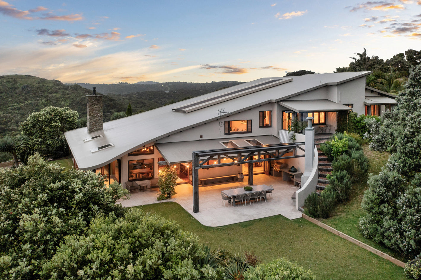 Modern house on Waiheke Island with a white exterior and large windows, surrounded by greenery.